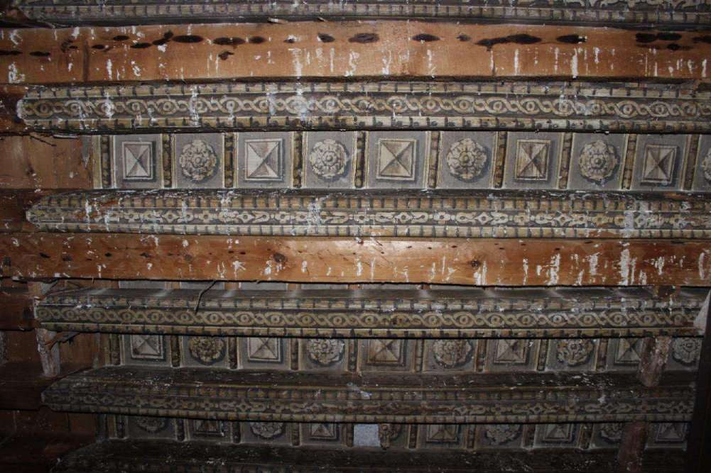 Detail of the painted coffered ceiling: braided beams and panels with flowers